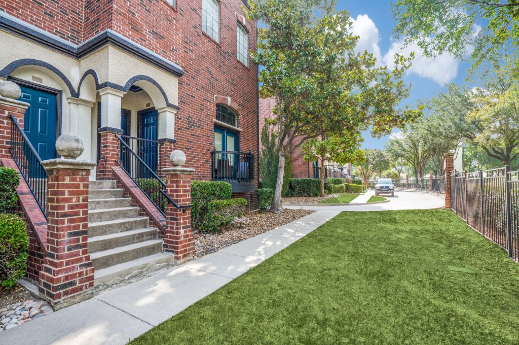 the front yard of a brick apartment building with grass and a green lawn at The  Ellington